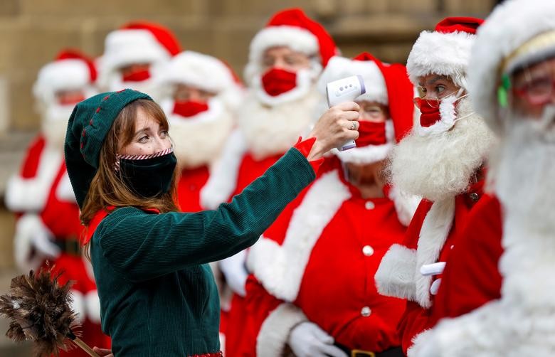 A woman dressed as an elf poses for a photo with attendees of the Ministry of Fun Santa School outside Southwark Cathedral, in London, Britain. REUTERS/John Sibley    